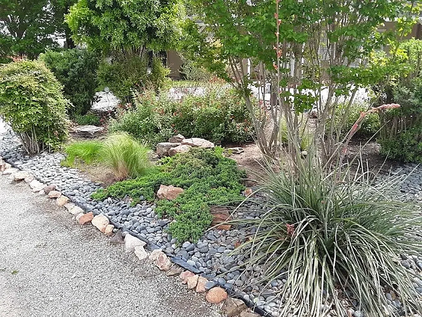 Rock border garden cared for by LBJ Gardens at a residential property in Kingsland, Texas near Lake LBJ